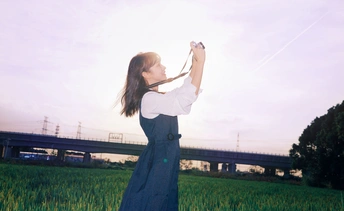 天空中的风筝 一个年轻女子在田野中放飞风筝