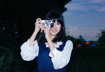 夜晚在田地里用相机拍照的年轻女子