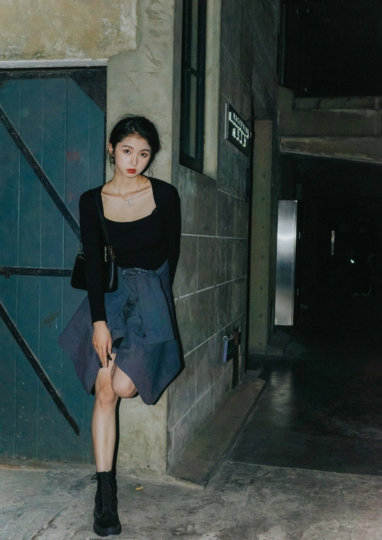 一位穿着黑色裙子的年轻女子站在门前