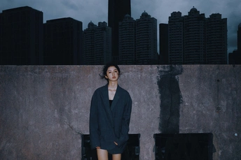 站在屋顶上的女人前面有一面墙 背景中有一个城市。