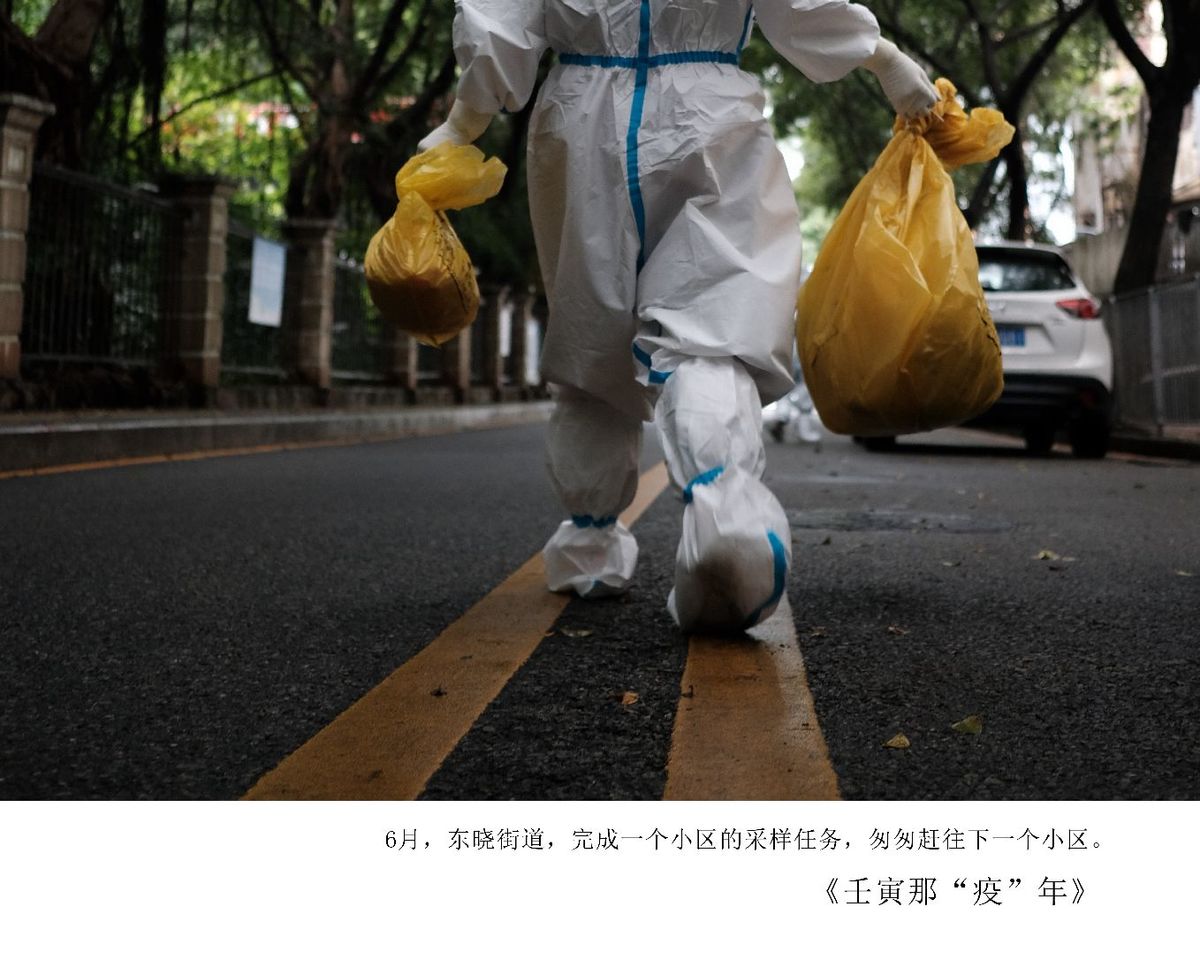 一个人穿着防护装备 拿着塑料袋穿过街道。