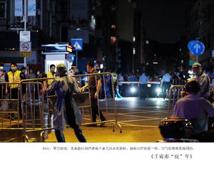 夜晚城市街道上站着一群人 身后有黄色栏杆。