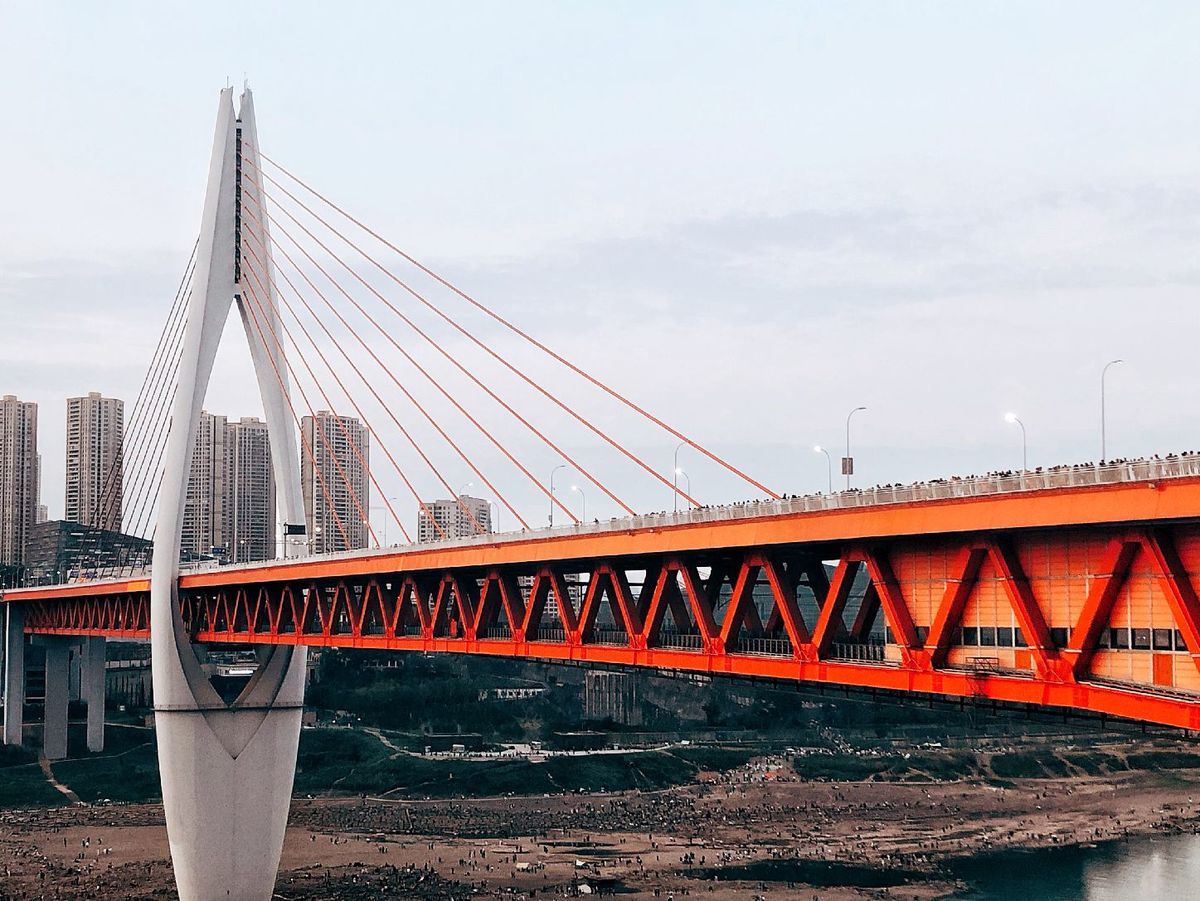 橙桥横跨河流宽度 背景中有一个城市。