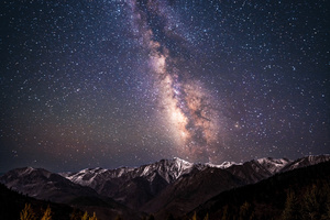 夜晚的山脉上有星星和星系在天空中。