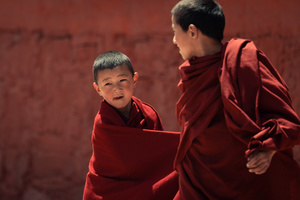 一个穿着红色长袍的年轻男孩站在和尚旁边