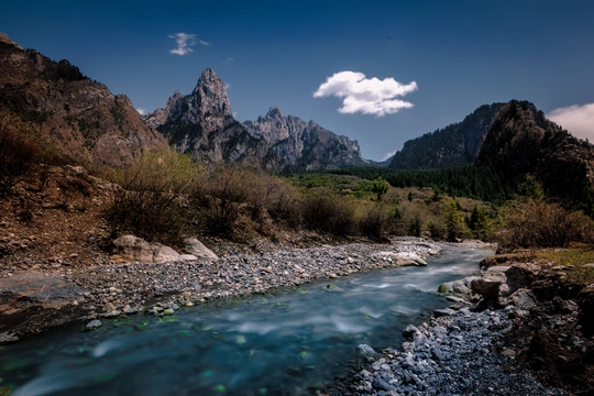 a river running through a valley with mountains in