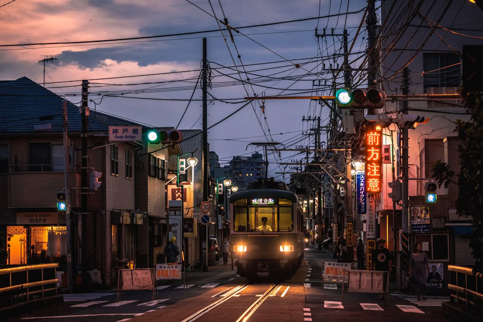 暮色中行驶在城市街道上的火车 周围有建筑和灯光。