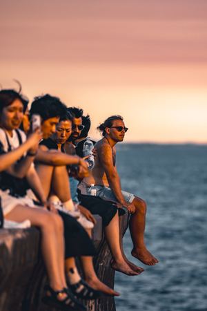 年轻人坐在海边的边缘观看日落。