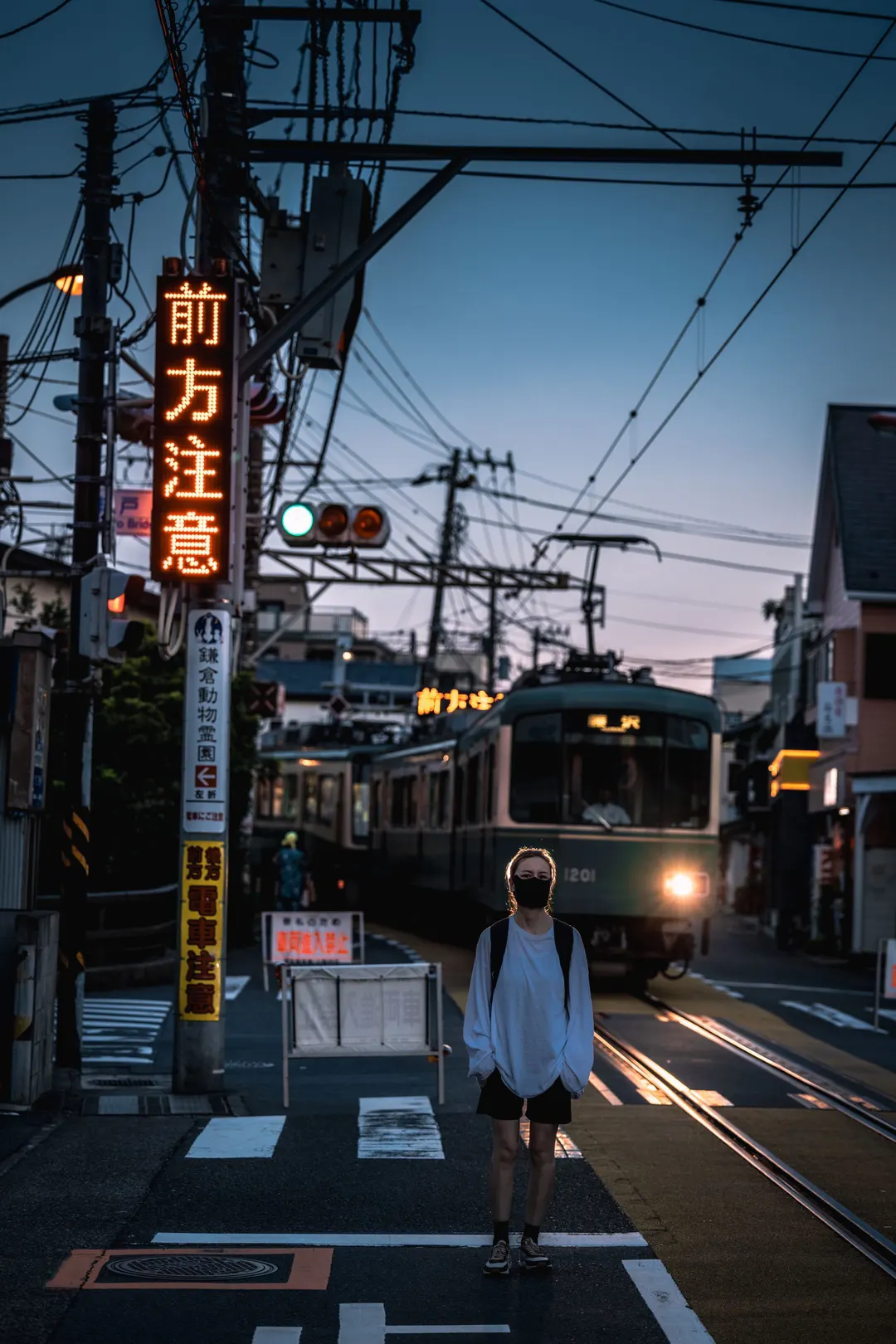 黄昏或夜晚站在城市街道的十字路口 火车在铁轨上的人