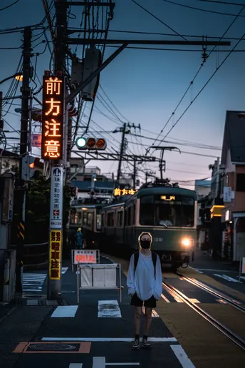 黄昏或夜晚站在城市街道的十字路口 火车在铁轨上的人