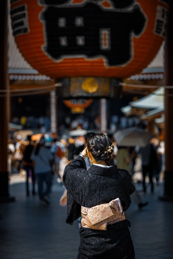 一个穿黑色和服的女人在人们经过时打电话