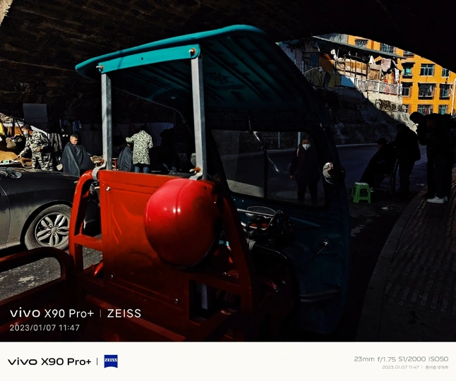 一些人在一辆红色汽车旁边站在桥下