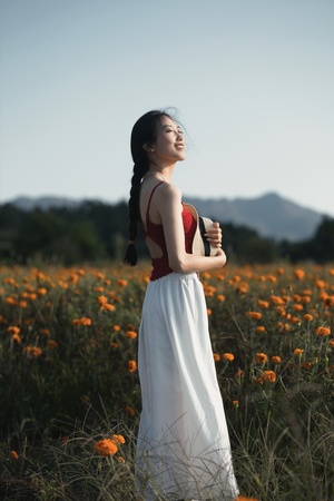 一位穿着白色连衣裙的年轻女子站在一片橙花田中