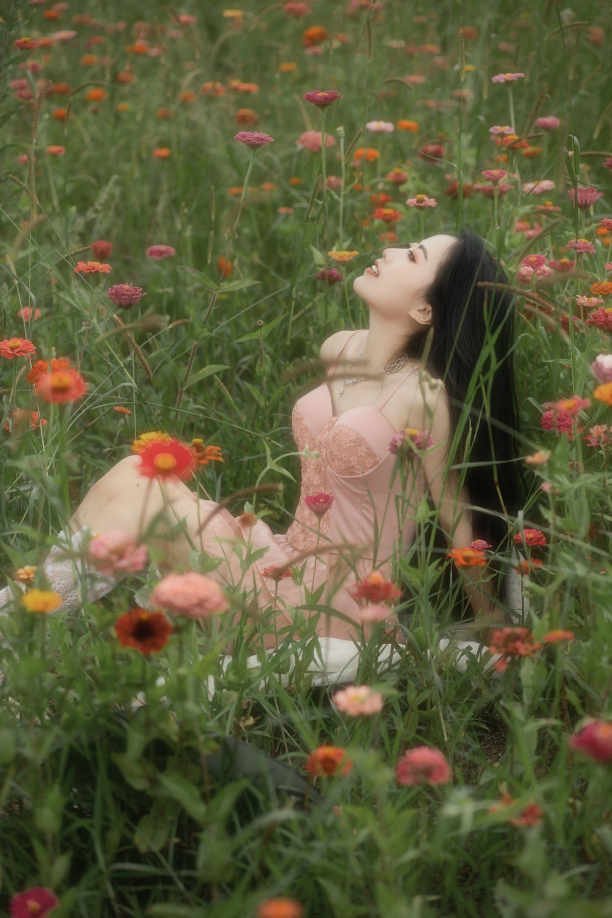 一位年轻女子坐在花丛和草地上