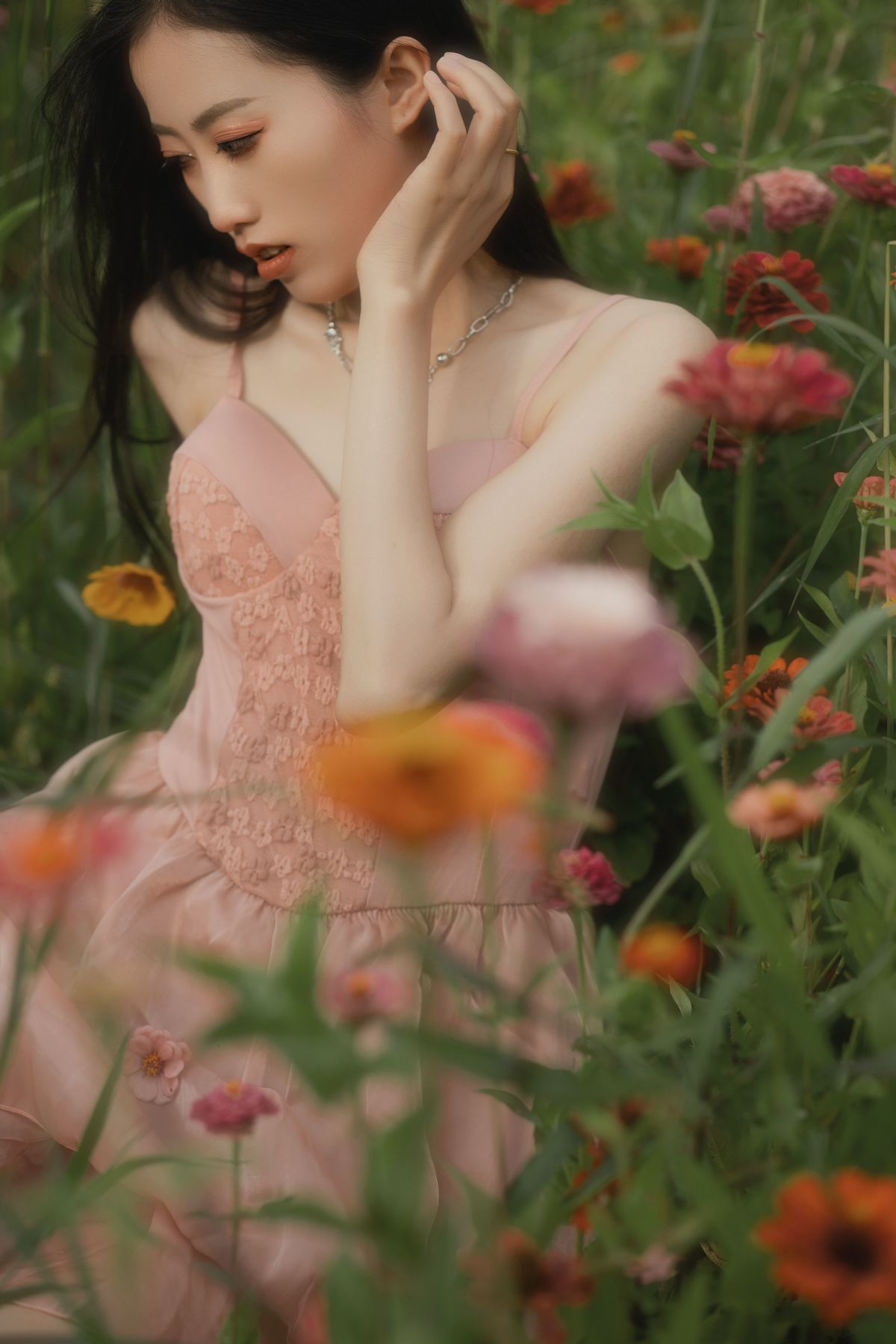 一个穿着粉红色裙子的年轻女子坐在花丛中