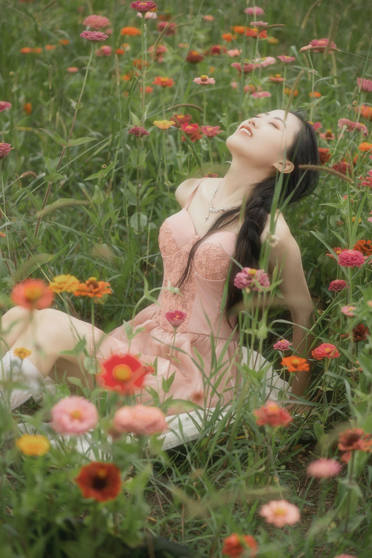 一位穿着美丽裙子的年轻女子坐在花丛和草地上