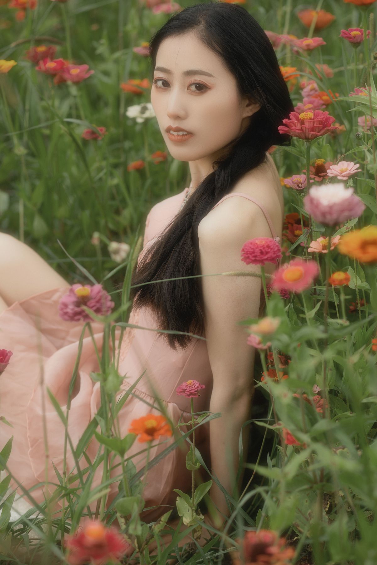 一位穿着美丽裙子的年轻女子坐在花丛中