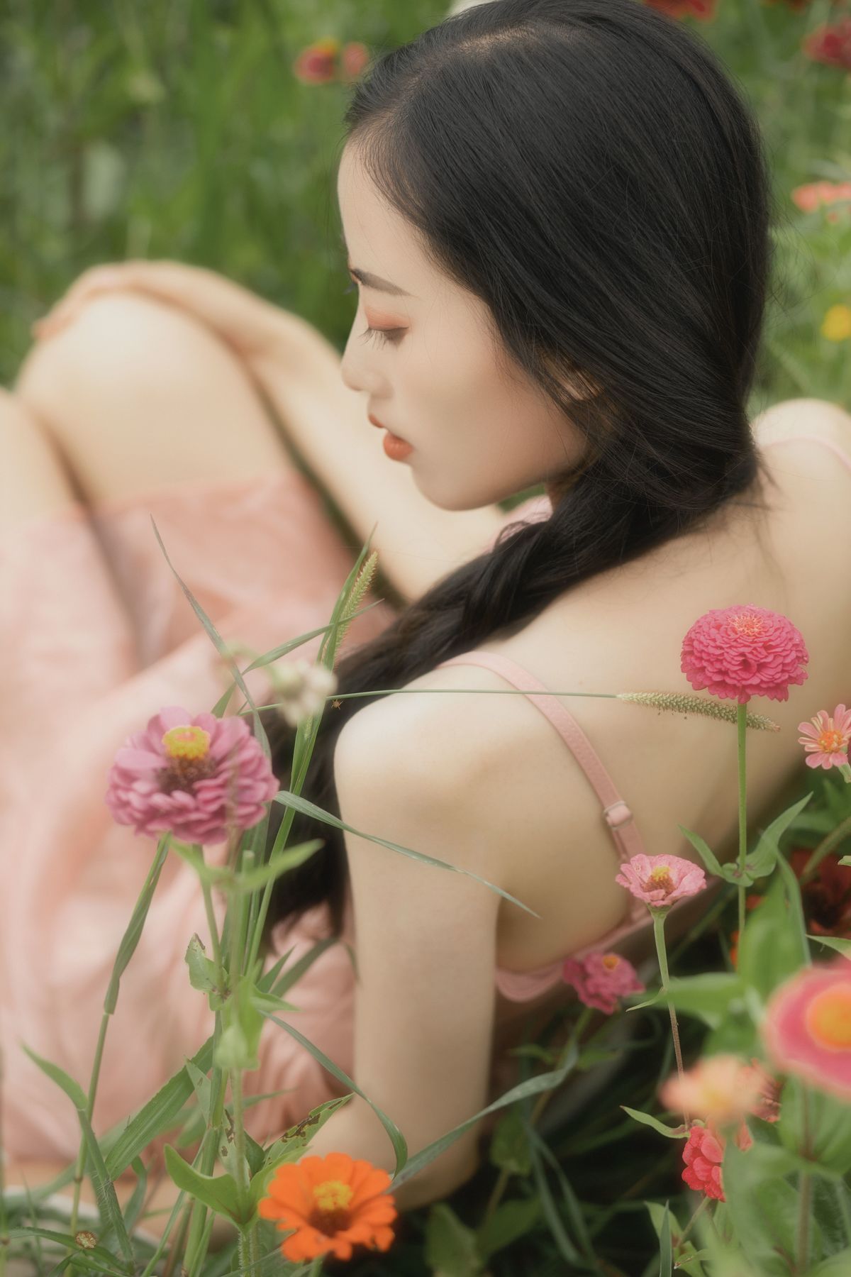一位穿着美丽裙子的年轻女子坐在花丛和草地上