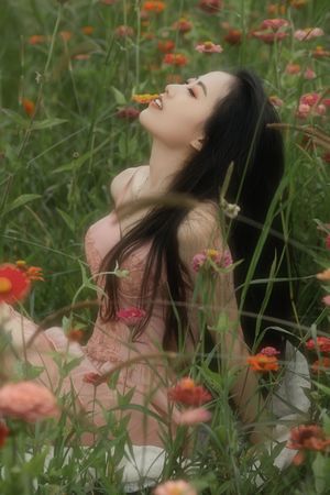 一个美丽的年轻女子坐在一片高草和花丛中