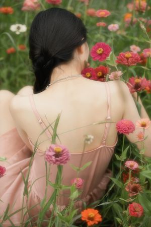 一位穿着粉红色裙子的女人坐在花丛中