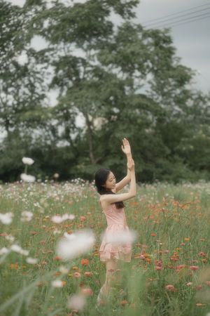 一个穿着粉红色裙子的年轻女子站在花丛中