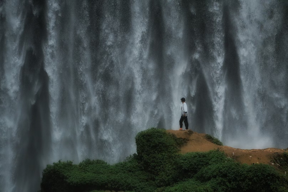 站在悬崖上的一名男子正在注视着一座大型瀑布