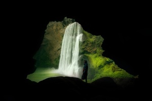 站在瀑布旁边的一个洞穴里的一名男子