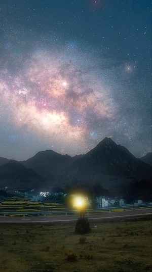 夜晚的山路 背景是山脉 天空中有星星。