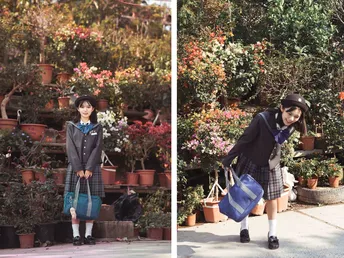 一位穿着校服的年轻女孩站在人行道上 手里拿着一个袋子 前面有一些植物和花。