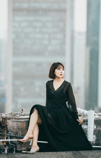 一个穿着黑色连衣裙的女人坐在手提箱上