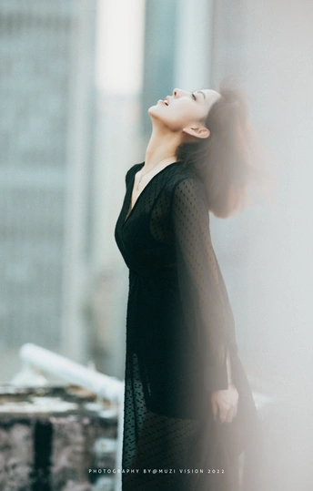 一个穿着黑色连衣裙的女人站在建筑区