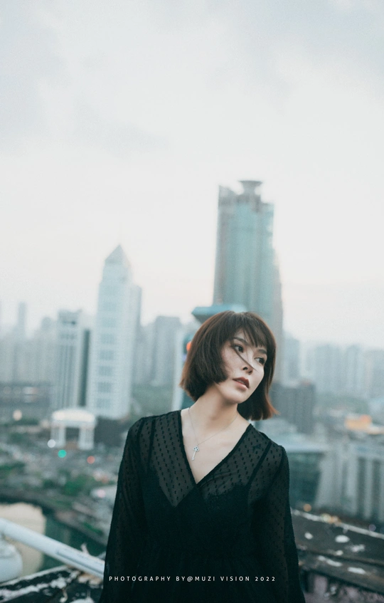一个穿着黑色连衣裙的女人站在屋顶上俯瞰着城市