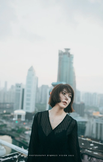 一个穿着黑色连衣裙的女人站在屋顶上俯瞰着城市