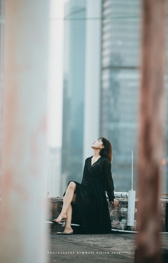 一个穿着黑色连衣裙的女人坐在建筑物上