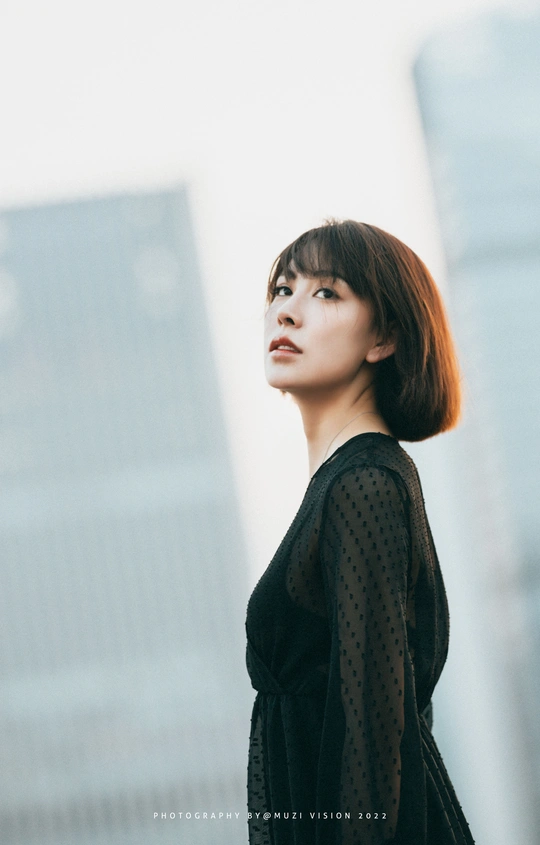 一个穿着黑色连衣裙的年轻女子站在一栋楼前