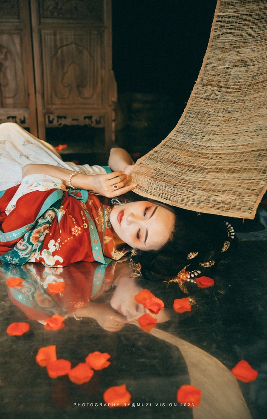 一个年轻女子躺在地上 全身覆盖着花瓣和鲜花。