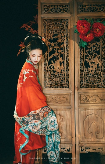 一位穿着红色和服的年轻女子站在一扇木门前