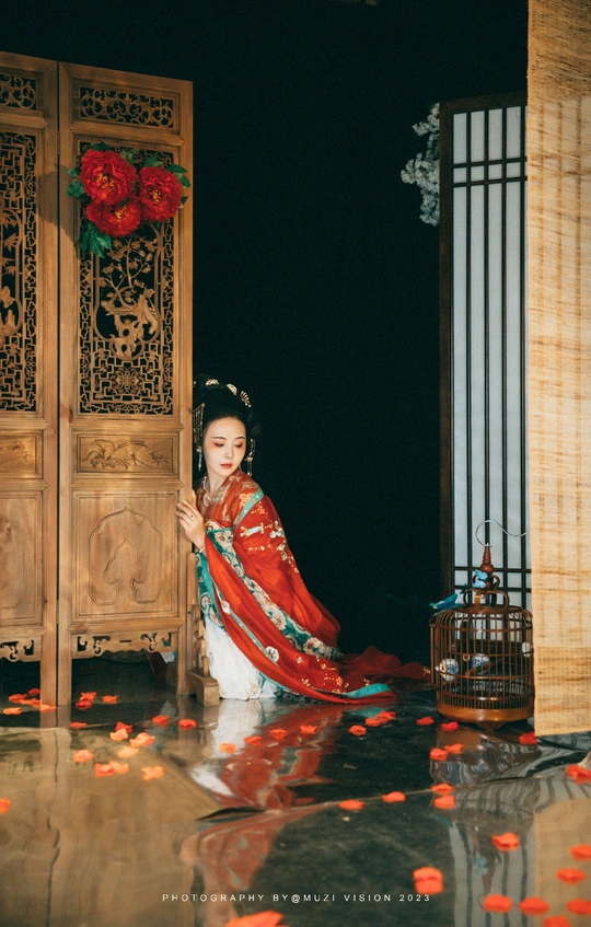 一位穿着传统红色裙子的年轻女子站在门前的水中。