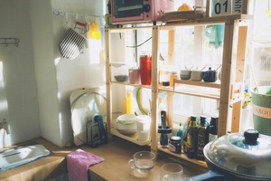 一个带有炉灶、微波炉、水槽、架子、锅和煎锅的小厨房