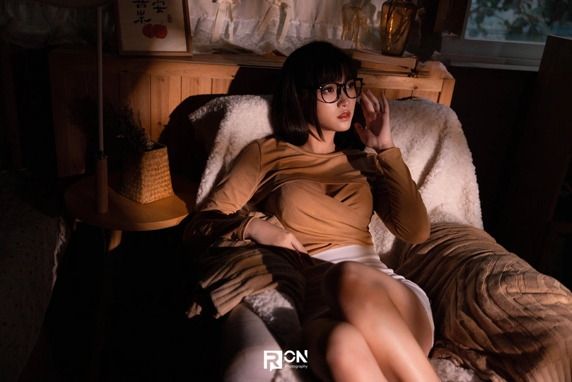 一个年轻女子坐在一个房间里 一个女孩躺在椅子上。