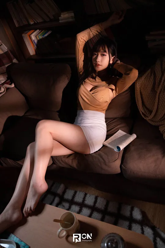 一个年轻女子坐在椅子上 双腿交叉 一本书放在沙发上。