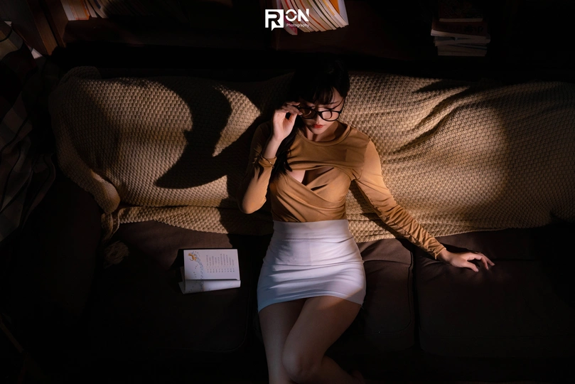 一个年轻女子坐在一个黑暗的房间里的一张床上