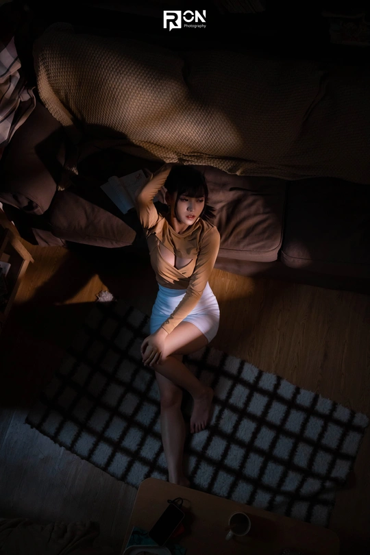 一个年轻女子坐在一个黑暗的房间里的一张床上