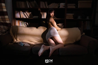 一个年轻女子坐在一个有很多书的房间里的一张沙发上