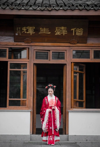 一位穿着红和服的年轻男子站在一栋建筑前