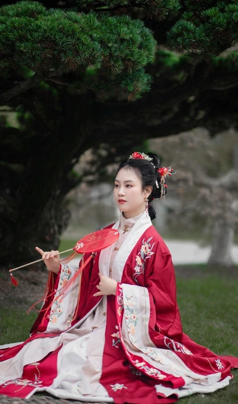 一位穿着传统服装的年轻女子 身着红色和白色连衣裙 手持雨伞。