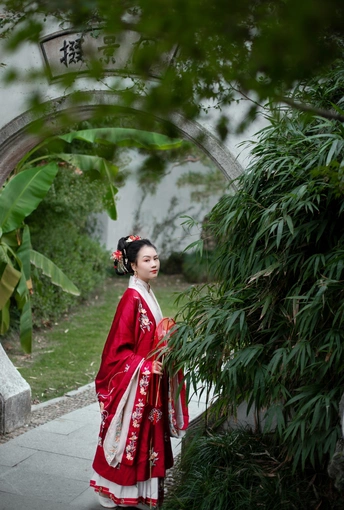 一位穿着红裙子的年轻女子站在拱门下