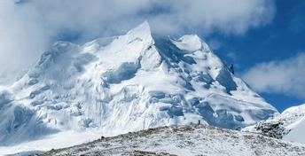 一座有人站在雪中顶峰的雪山