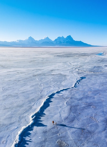沙漠中一座被冰封的湖上的冰裂缝 背景是山脉。