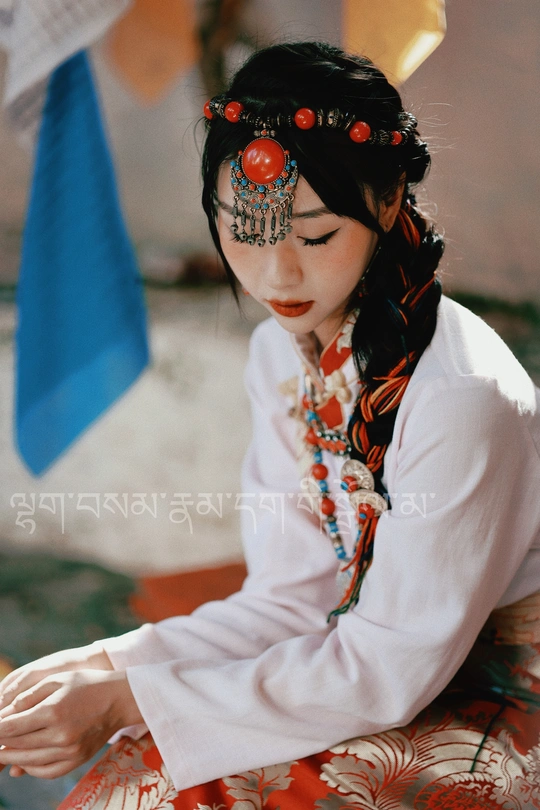 一个穿着传统服装的年轻女孩坐在地上